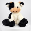 Black-and-white plush cow sitting on a white pedestal