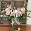 Pink and white floral arrangement in a glass vase with a plaid ribbon