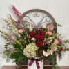 Mixed bouquet of roses, lilies, and hydrangea in a white vase with a ribbon