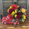 Colorful flower arrangement in a red ceramic truck container