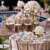Blush and white rose centerpieces on gold stands at an outdoor table setting.