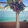 Tropical floral arch with red blooms and white draping by the ocean