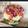 Mixed pink, coral, and purple bouquet in a clear glass vase