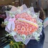 Large bouquet of pink roses with white filler flowers and a pink ribbon