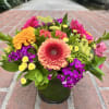 Colorful mixed bouquet in a glass vase with gerbera daisies, carnations, and chrysanthemums
