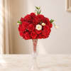 Red rose arrangement in a tall clear vase with a few white blooms