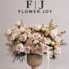 A luxurious arrangement of champagne and blush roses, delicate spray roses, and