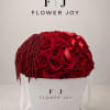 A premium Flower Joy gift box filled with rich red roses, cascading