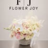 A graceful arrangement of ivory roses, white orchids, hydrangeas, ranunculus, and soft