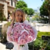 Woman holding a large bouquet of pink roses wrapped in white paper