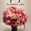 Large pink and peach flower arrangement in a dark vase with ribbon