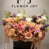 Large pastel floral arrangement in a dark container with cascading blooms