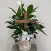 White peace lilies in a wicker basket with a wooden cross and white ribbon