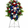 Standing floral wreath with red and white flowers and a blue ribbon on an easel