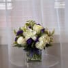 White roses and lilies in a glass vase with purple accents