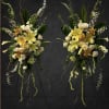 Two tall floral sprays with yellow lilies and white roses on stands