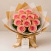 Bouquet of pink roses wrapped in white and gold paper with a satin ribbon