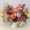 Colorful mixed bouquet in a white vase with dahlias, roses, and blue flowers