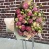 Bouquet of pink roses and pale lisianthus wrapped in pastel paper