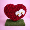 Heart-shaped red rose arrangement with two white orchids on a green base