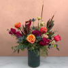 Mixed bouquet of orange and pink roses in a dark glass vase
