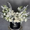 White roses and snapdragons arranged in a black hatbox.