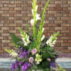 Tall floral arrangement with purple and white blooms in a white vase