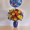 Birthday balloon above a colorful flower arrangement in a blue vase