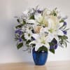 White lilies and daisies arranged in a blue vase