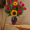 Red roses and sunflowers arranged in a purple glass vase