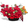 Red roses arranged in a black basket with orange tulips