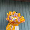 Bouquet of lavender and yellow roses wrapped in bright orange paper