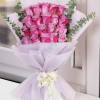 Bouquet of pink roses wrapped in pale lavender paper with a white ribbon