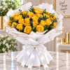 Bouquet of yellow roses wrapped in white paper with gold trim and a white ribbon