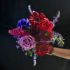 Handheld bouquet with red, lavender, and blue flowers