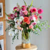 Tall mixed bouquet of pink, white, and coral flowers in a glass vase