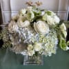 An elegant clear glass vase brimming with periwinkle blue hydrangea, white roses