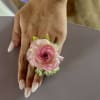 Pink ranunculus wrist corsage on a hand