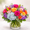 Colorful bouquet of roses, hydrangea, and lilies in a glass vase