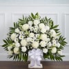White floral standing arrangement with a white ribbon on a pedestal base