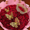 Bouquet of red roses wrapped in pink paper with gold butterfly accents