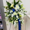 Large white floral standing spray with blue ribbon on an easel