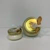 Two small candle jars with gold lids and wooden spoons tied on top