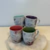 Four floral quote mugs with colored interiors arranged on a round tray