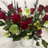 Red roses and pale green flowers arranged in a white vase