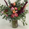 Mixed bouquet of pink and peach flowers in a glass vase