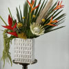 Tropical flower arrangement in a white geometric vase on a pedestal