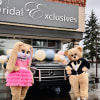 Bunny and bear mascots pose by a balloon-decorated black SUV in front of a bridal shop.