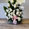 White rose bouquet with a pink ribbon and dark green leaves