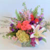 A modern clear cube,filled with bright mixed summer flowers,roses and ferns,that will